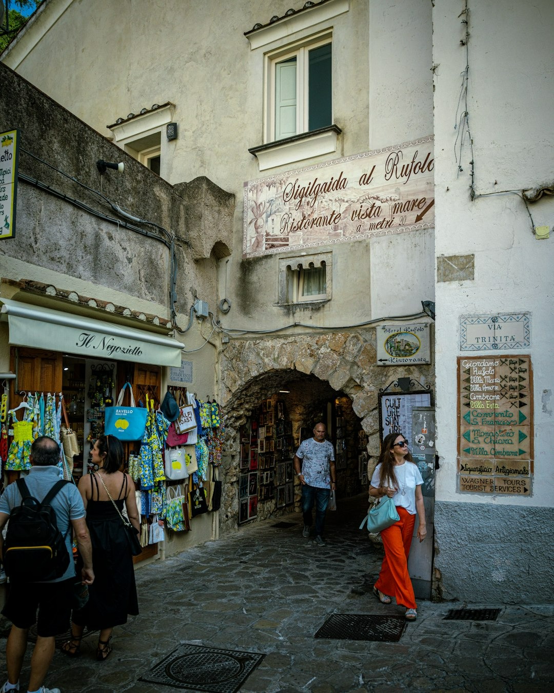 fashionable woman in red pants carrying an aqua bag walks through the cobblestone streets of Amalfi