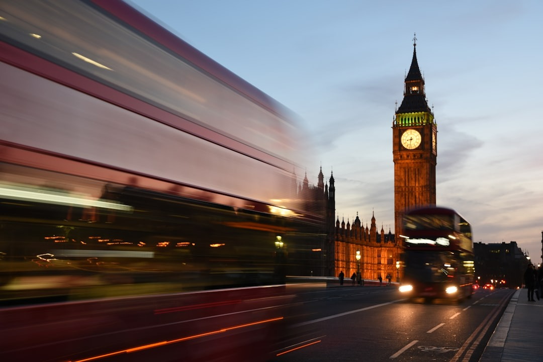 Sunset near Big Ben clock tower in London as buses and traffic zooms past camera